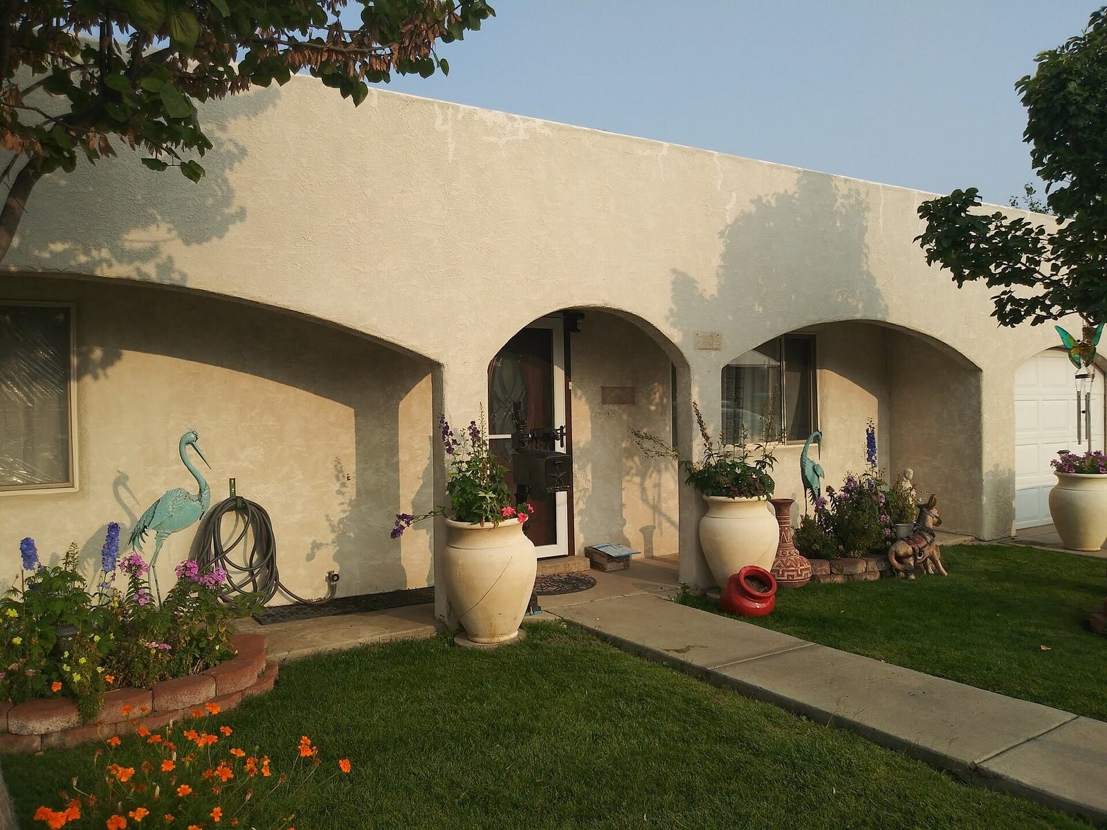 Southwest stucco home with arched entry, fresh paint and flowering planters