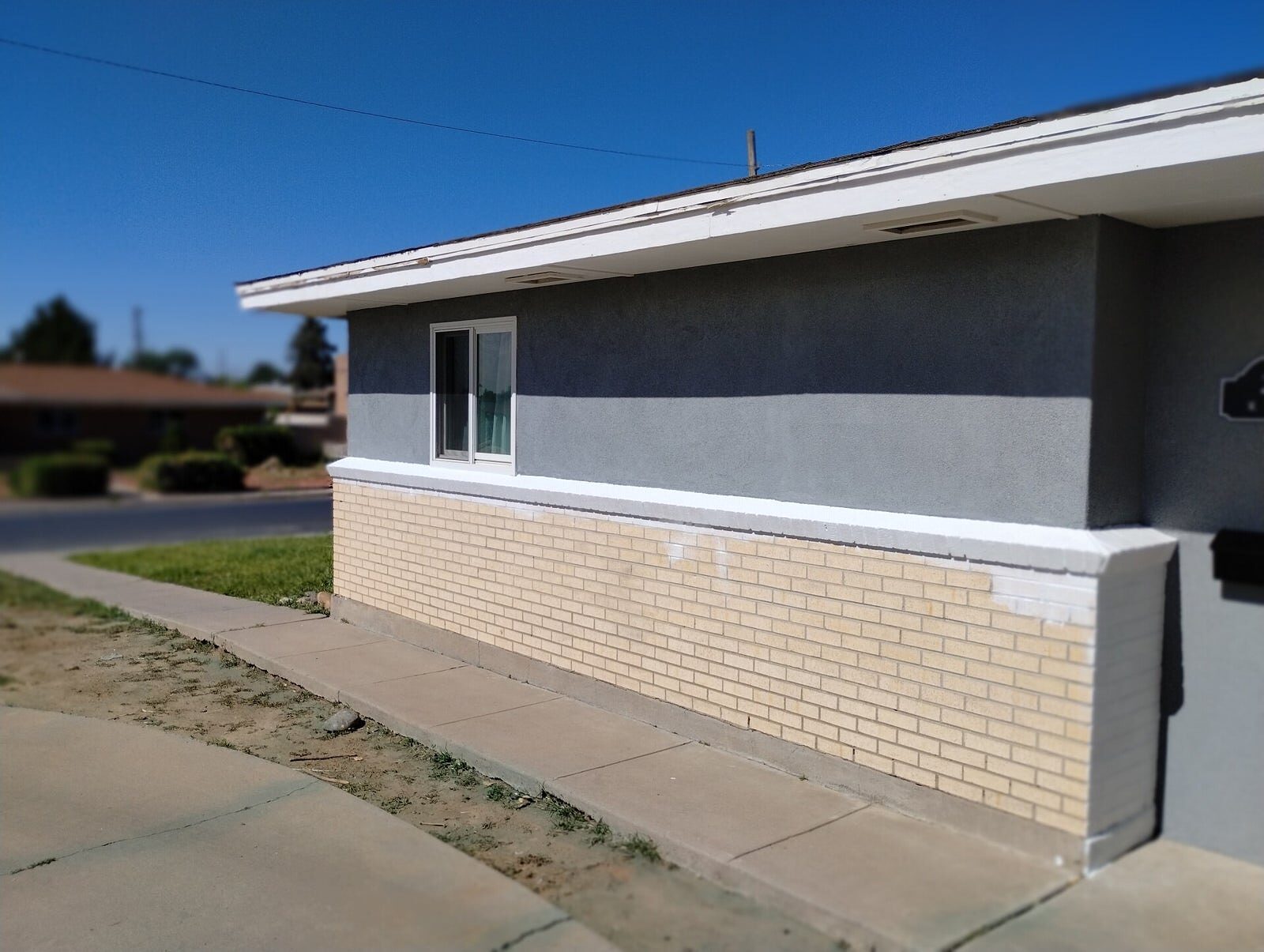 Long single-story home with fresh gray exterior paint and brick accent wall