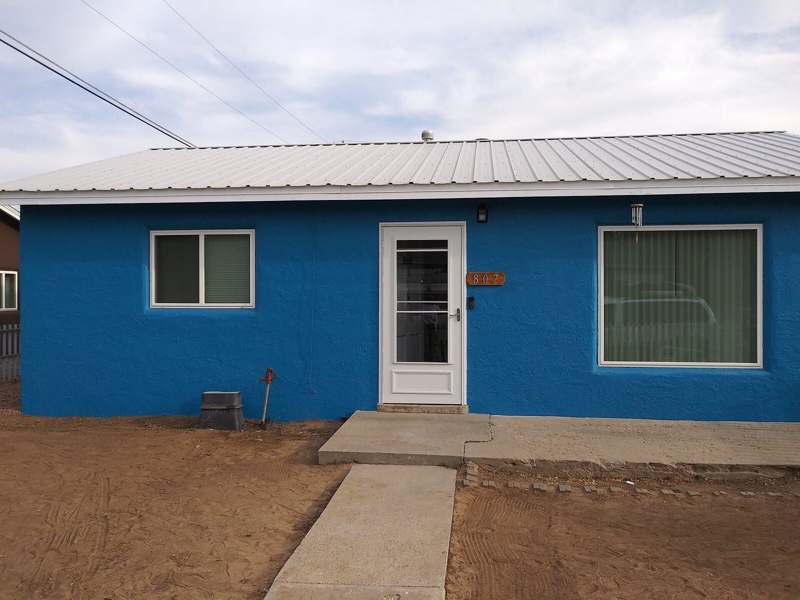 Bold blue home exterior with metal roof, freshly painted